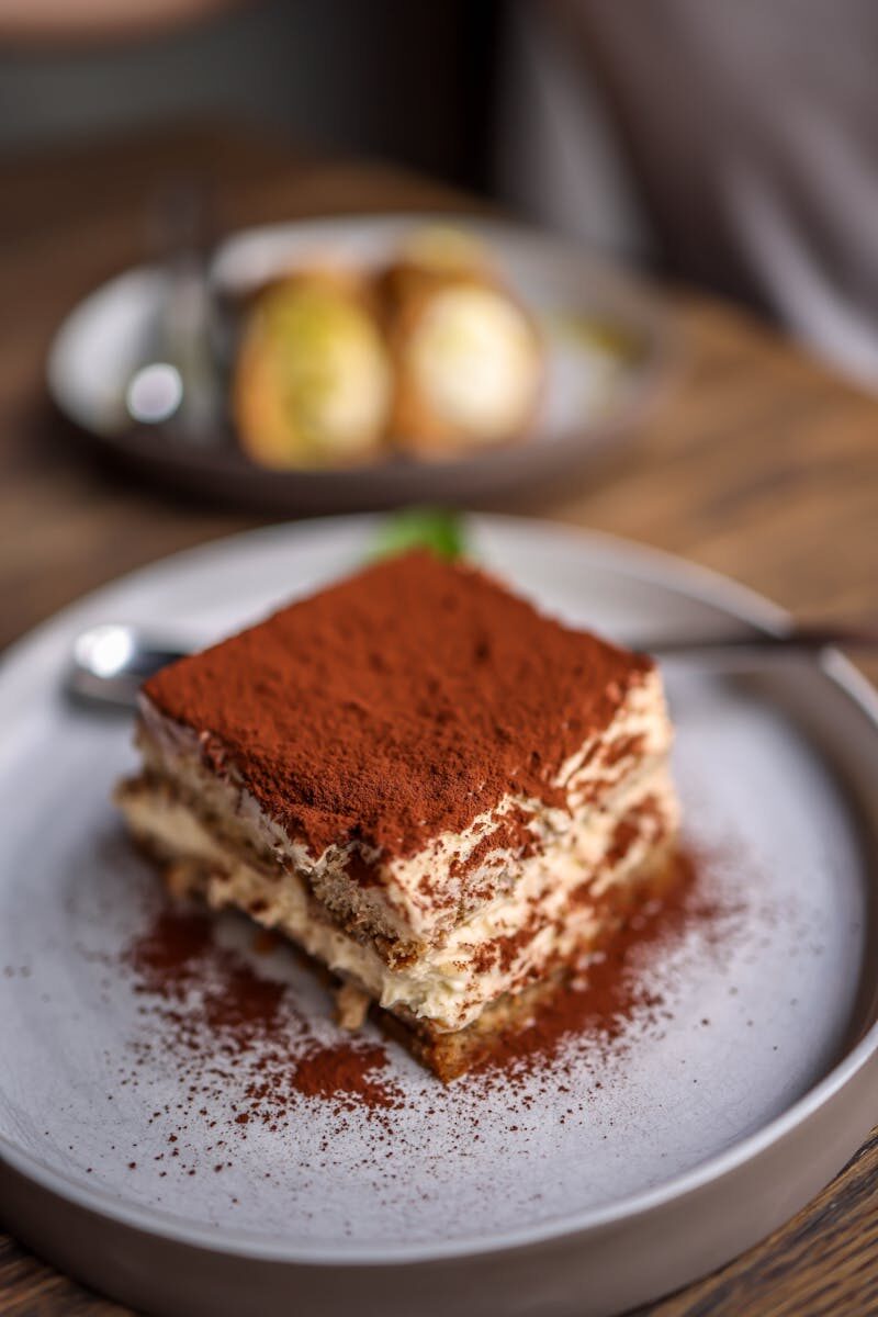Close-up of a delectable tiramisu slice on a rustic table, perfect for dessert lovers.