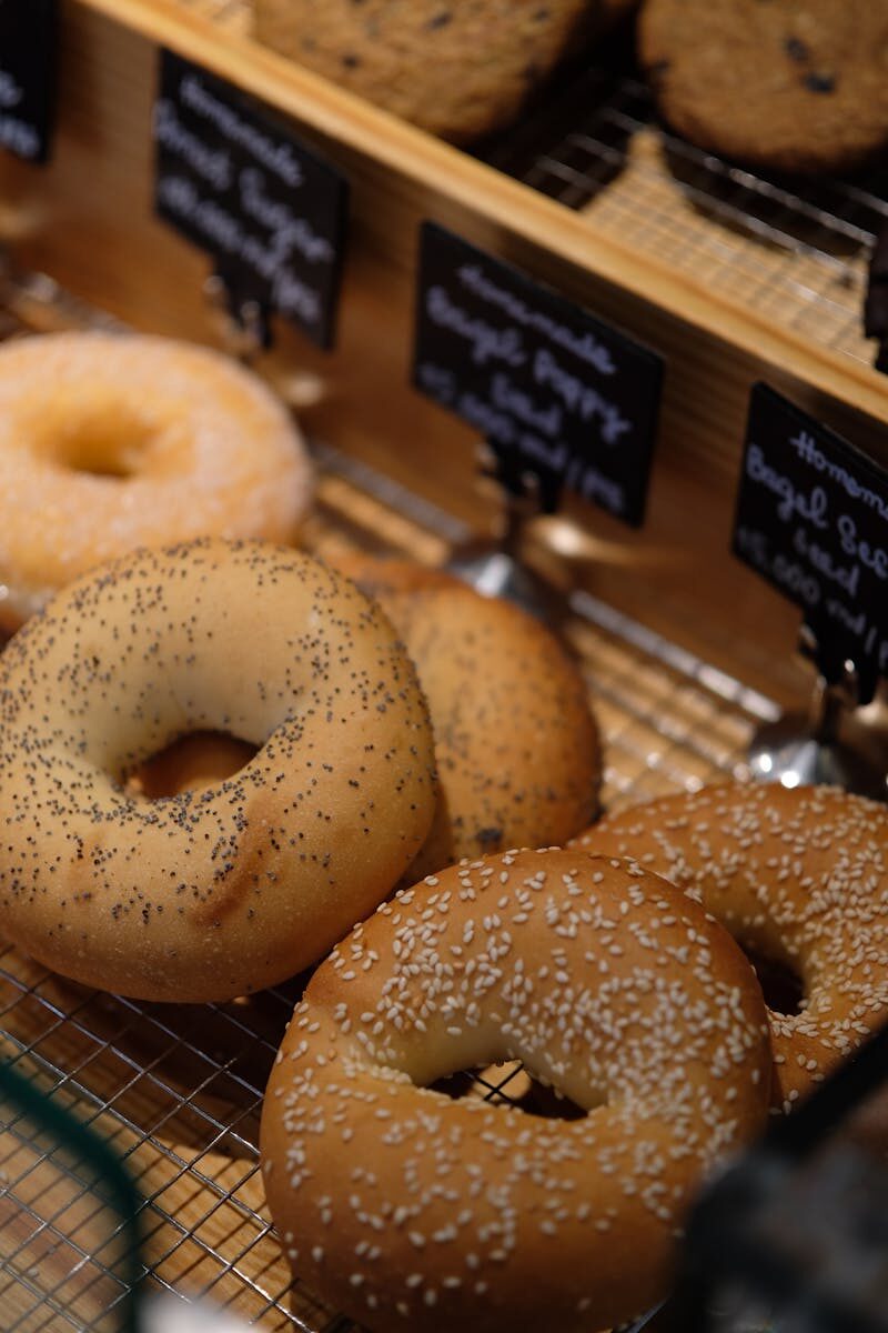 A close-up of various types of fresh bagels in a bakery setting.