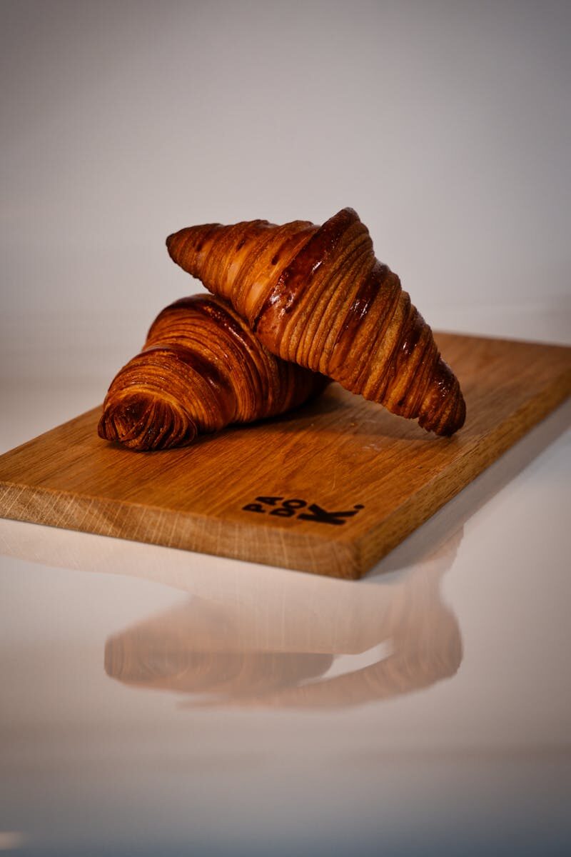 Delicious artisan croissants resting on a wooden board, highlighting their flaky texture and freshness.